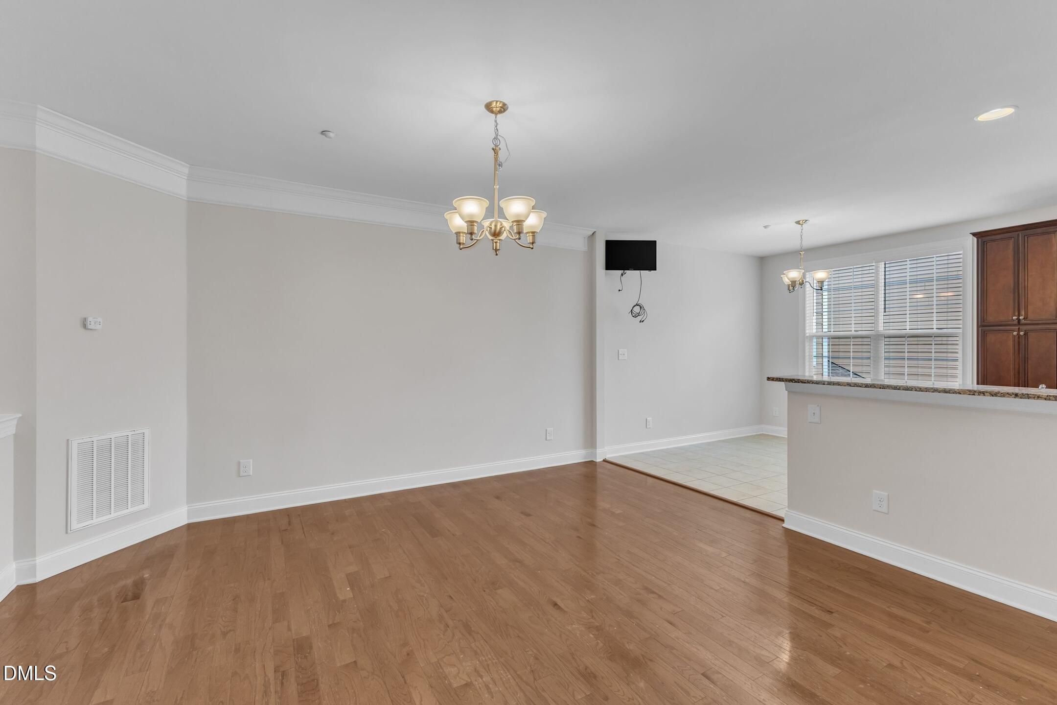 9211 Calabria Drive, Unit 104 Raleigh, NC 27617 - Photo 8 of 45 an empty room with wooden floor chandelier and windows