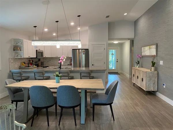 a kitchen with stainless steel appliances a dining table chairs and wooden floor