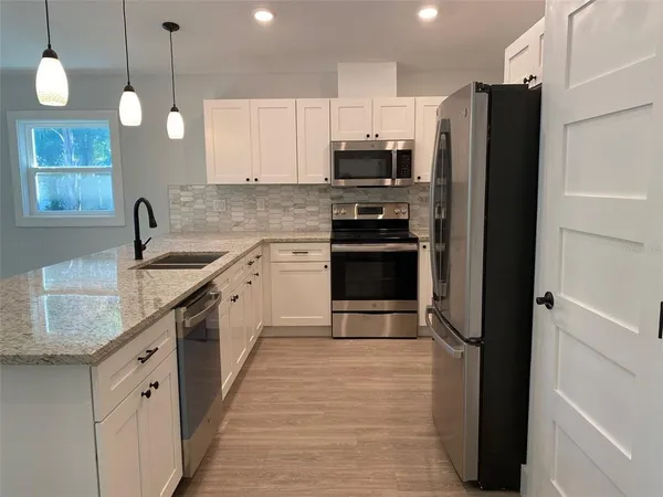a kitchen with stainless steel appliances granite countertop a sink stove and refrigerator