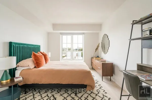 a bedroom with a bed a mirror on dresser and a window