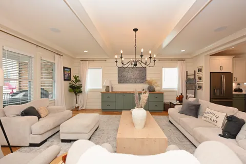 a living room with furniture a chandelier and a flat screen tv