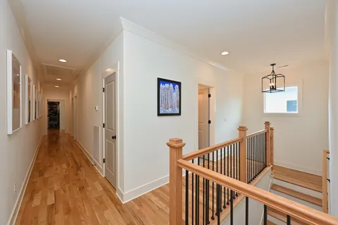 a view of a hallway with wooden floor and stairs