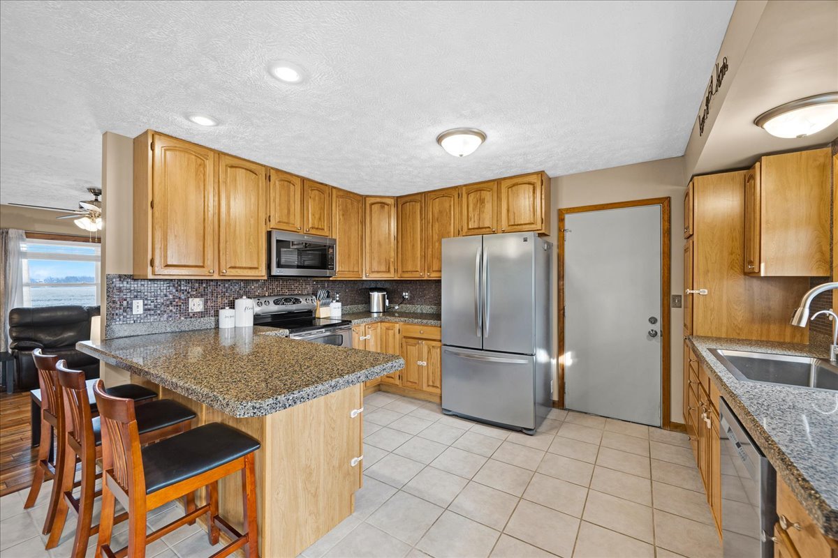 505 West North Street Danvers, IL 61732 - Photo 11 of 45 a kitchen with stainless steel appliances granite countertop a stove a refrigerator a sink a oven with a dining table and chairs