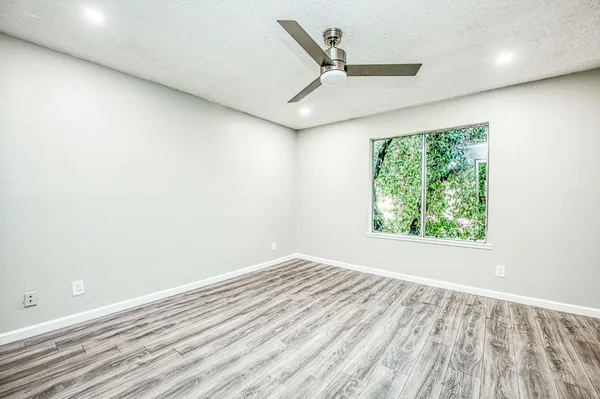 an empty room with wooden floor and windows