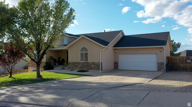 1797 Sunset Road Enoch, UT 84721 - Photo 77 of 80 Stucco exterior featuring stone accents, an attached two-car garage, covered porch, and a manicured front lawn