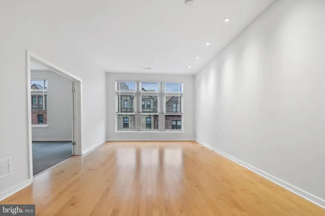 a view of empty room with wooden floor and fan