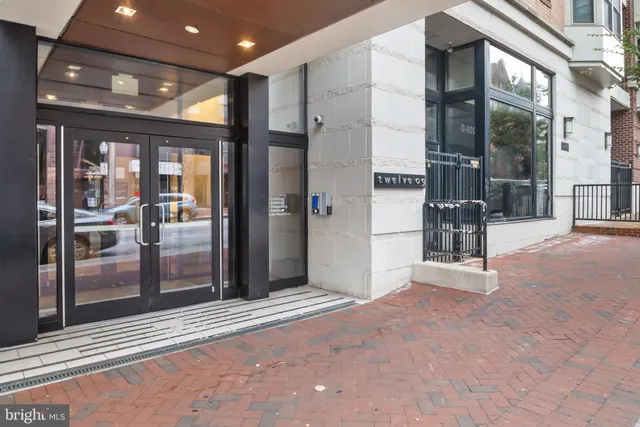 a view of a hallway with stainless steel appliances granite countertop a refrigerator and a sink