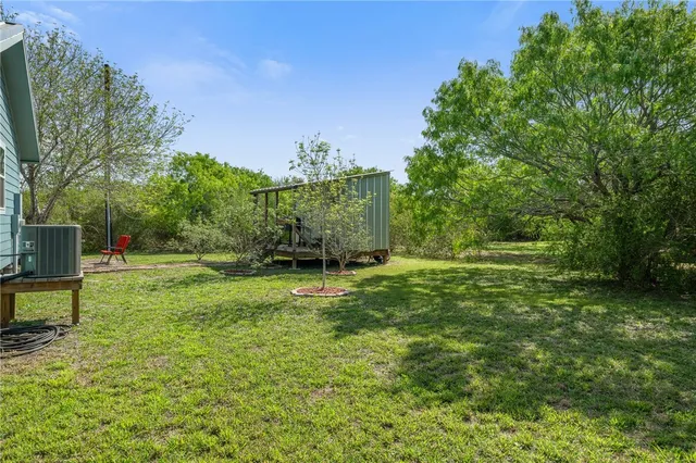 a view of a house with a big yard plants and large trees