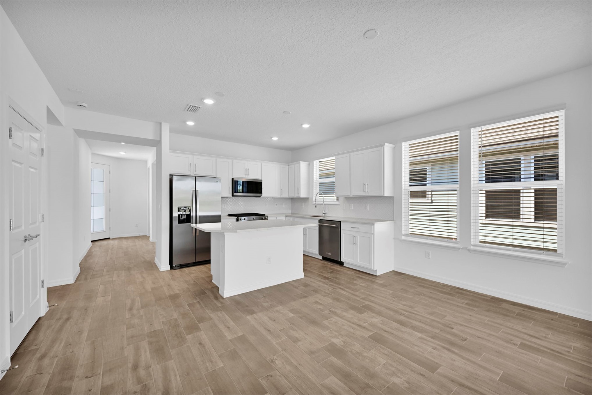 285 Ecliptic Loop Yulee, FL 32097 - Photo 3 of 42 a large white kitchen with kitchen island a sink wooden floor and a refrigerator