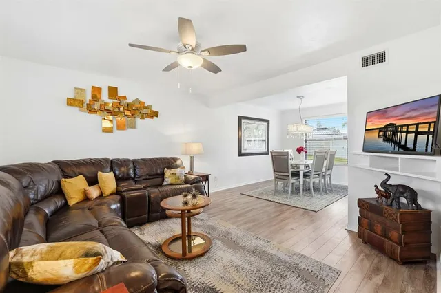 a large white kitchen with stainless steel appliances granite countertop a stove a sink dishwasher and white cabinets with wooden floor