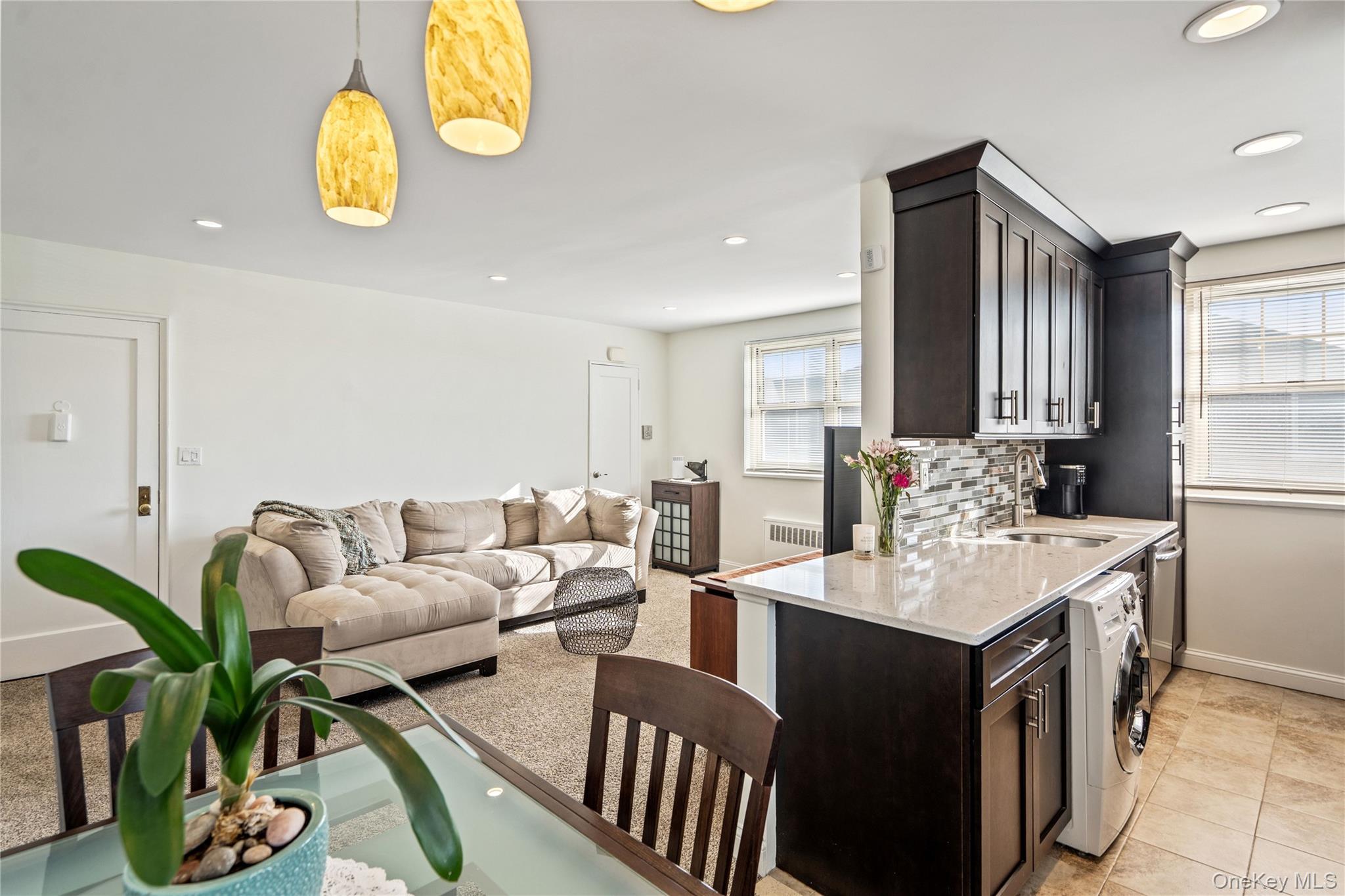 63-09 252nd Street, Unit 41322 Queens, NY 11362 - Photo 3 of 25 a living room with furniture a chandelier and kitchen view