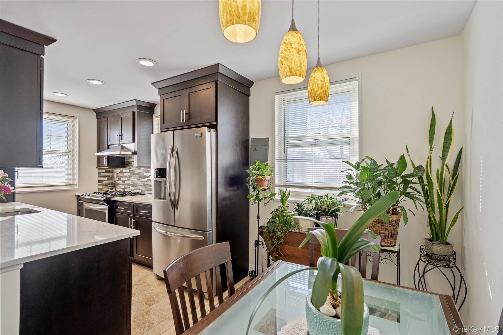 63-09 252nd Street, Unit 41322 Queens, NY 11362 - Photo 4 of 25 a kitchen with stainless steel appliances a dining table a potted plant and cabinets