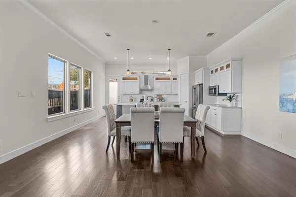 a kitchen with stainless steel appliances a dining table chairs and wooden floor