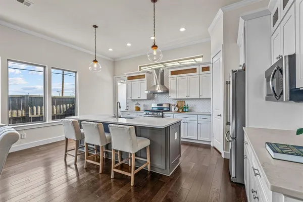 a kitchen with stainless steel appliances granite countertop a stove a refrigerator a oven a sink with island chairs and wooden floor