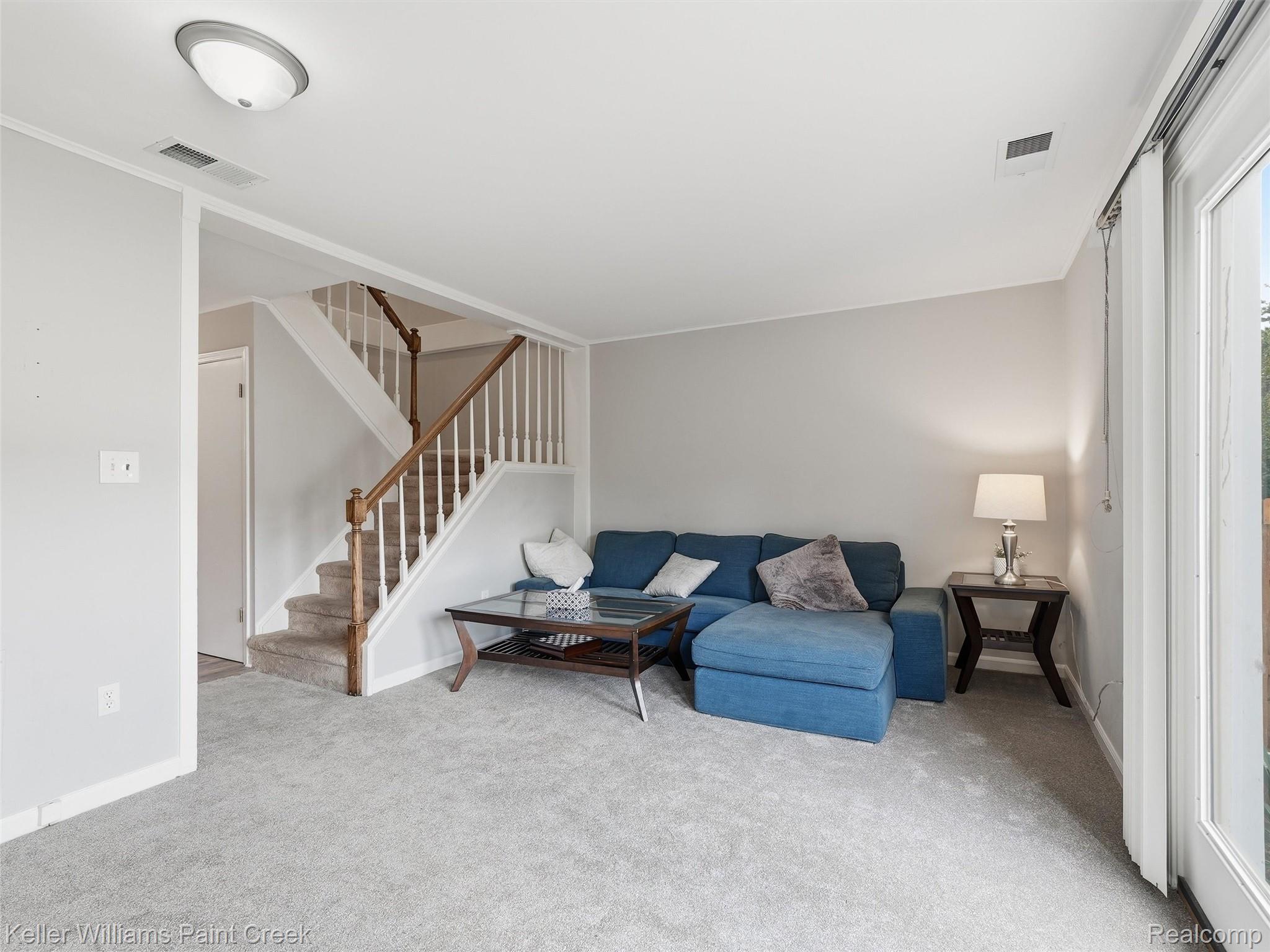 1208 Lear Court Rochester, MI 48307 - Photo 11 of 28 Carpeted flooring, painted walls, staircase with wood handrail, ceiling-mounted light fixture, sliding glass door
