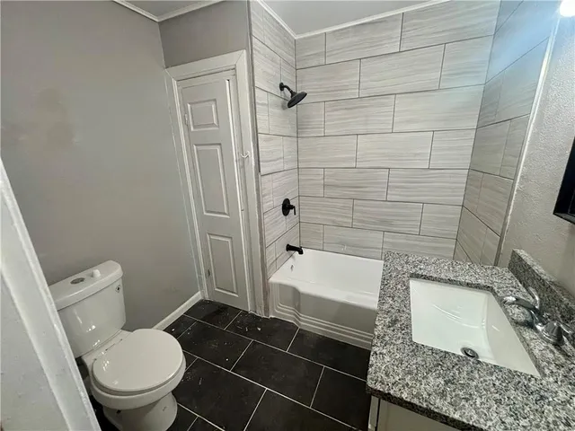 a bathroom with a granite countertop toilet and a sink