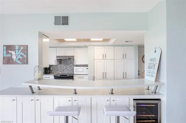 a kitchen with stainless steel appliances kitchen island granite countertop a sink and a white cabinets