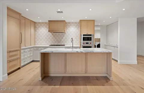 a large kitchen with stainless steel appliances granite countertop a stove a sink and a refrigerator