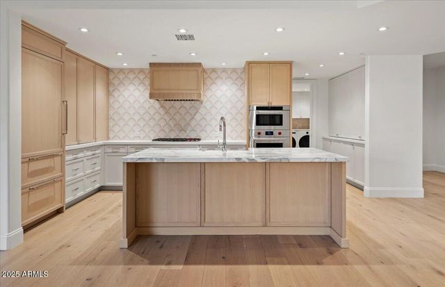 a large kitchen with stainless steel appliances granite countertop a stove a sink and a refrigerator