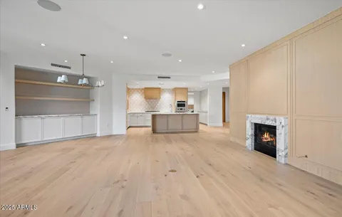 an empty room with wooden floor fireplace and windows