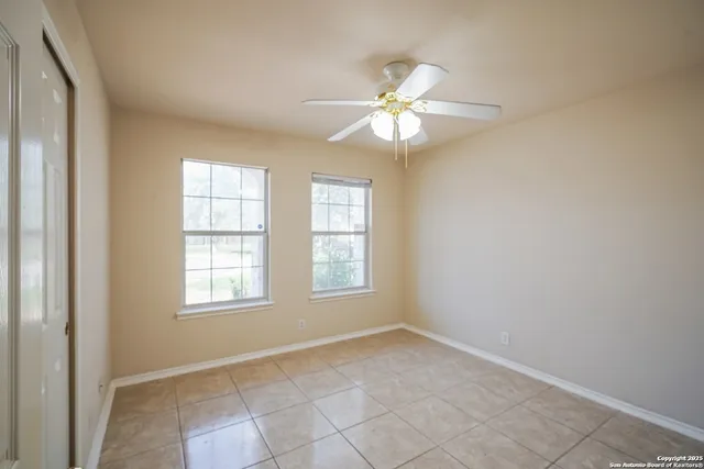 an empty room with windows and fan