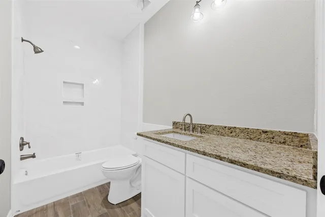 a bathroom with a granite countertop sink and mirror with bathtub