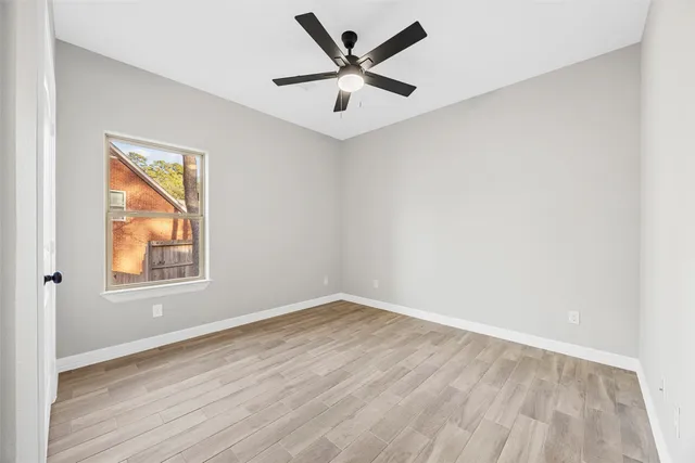 an empty room with a window and a ceiling fan