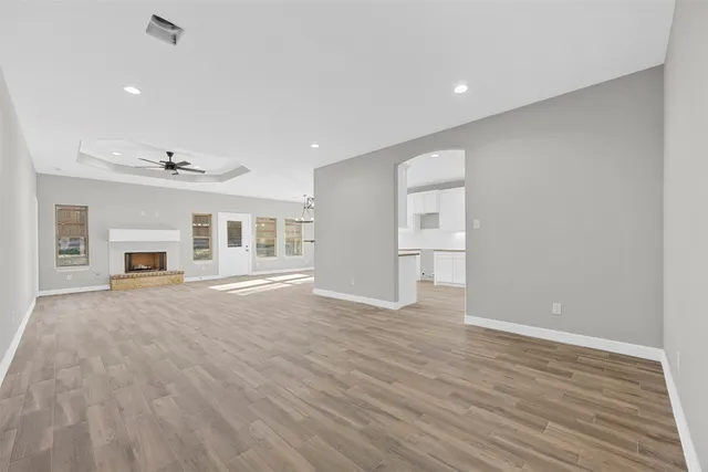 a view of empty room with wooden floor and kitchen view