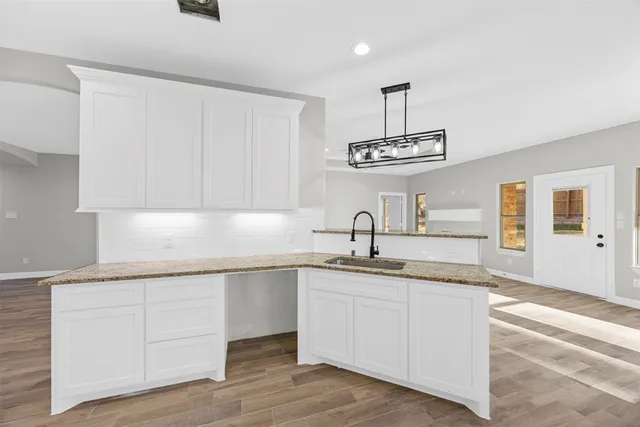a kitchen with a sink dishwasher a stove and white cabinets with wooden floor