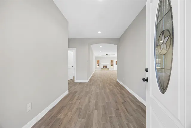 a view of a hallway with wooden floor and a bathroom