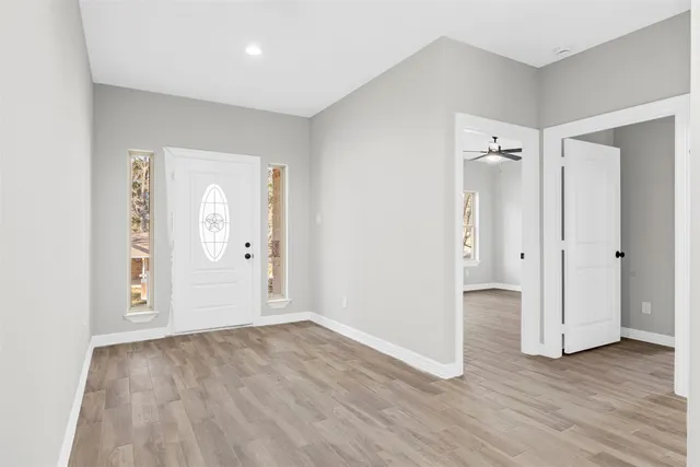an empty room with wooden floor & windows