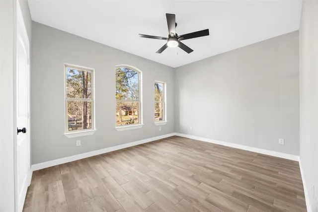a view of an empty room with a window and wooden floor