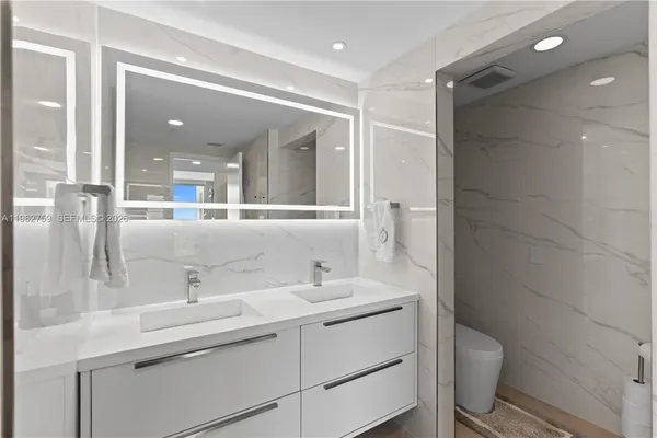 a bathroom with a double vanity sink toilet and shower