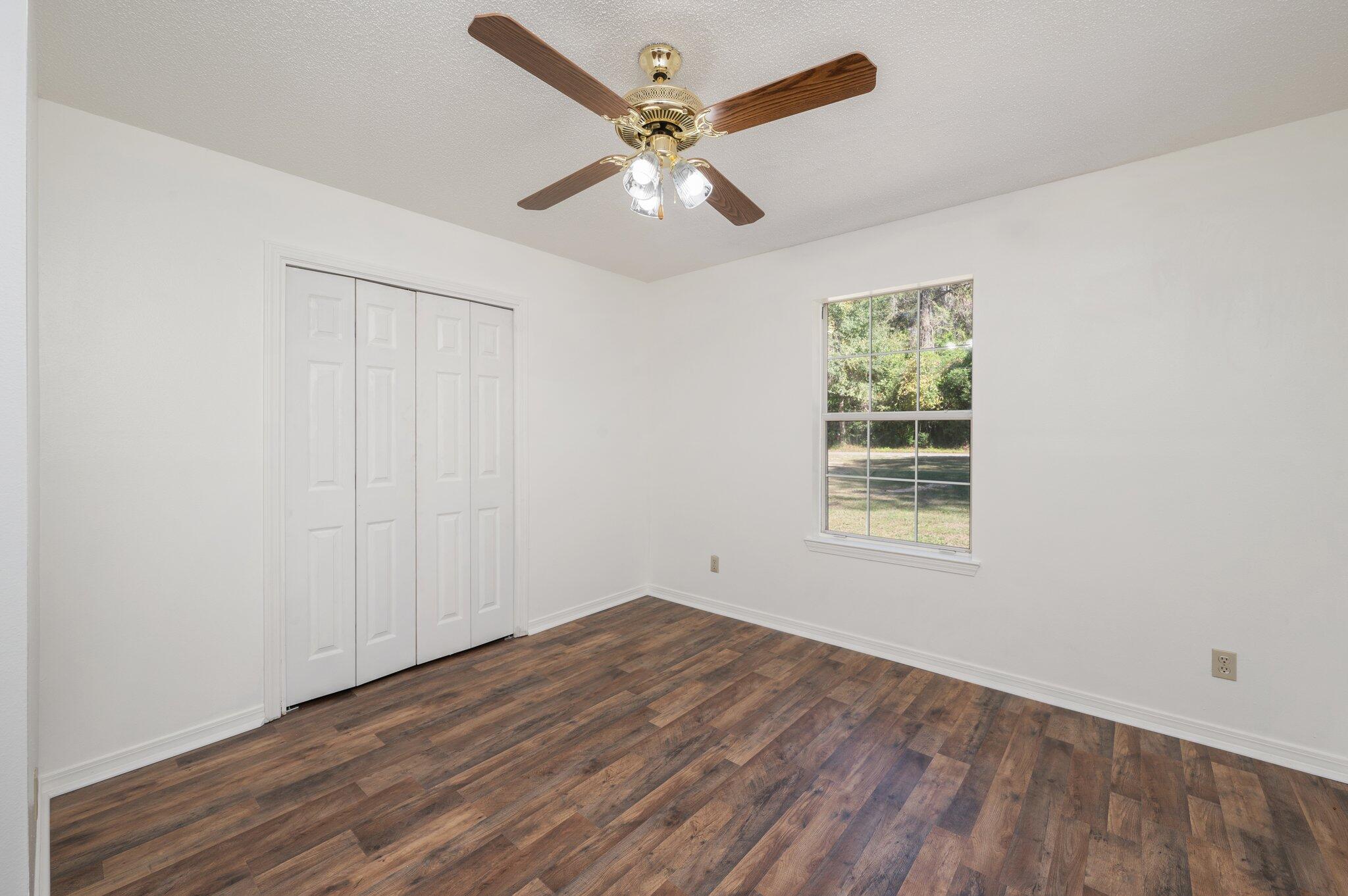 624 Hill Street DeFuniak Springs, FL 32435 - Photo 16 of 34 an empty room with wooden floor chandelier fan and windows
