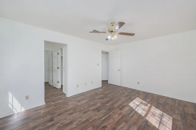 an empty room with wooden floor and ceiling fan
