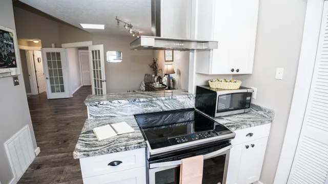 a kitchen with kitchen island granite countertop a stove and a cabinets