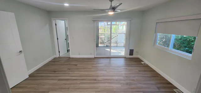 a view of an empty room with wooden floor and a window