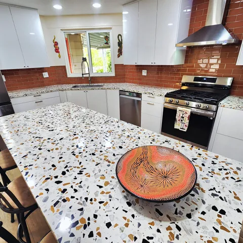 a kitchen with a stove a sink a window and a counter top space