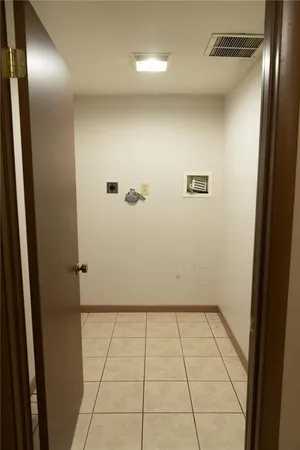 a view of a refrigerator in kitchen and an empty room with wooden floor