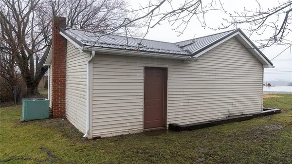 a view of a white house with a small yard and a large tree
