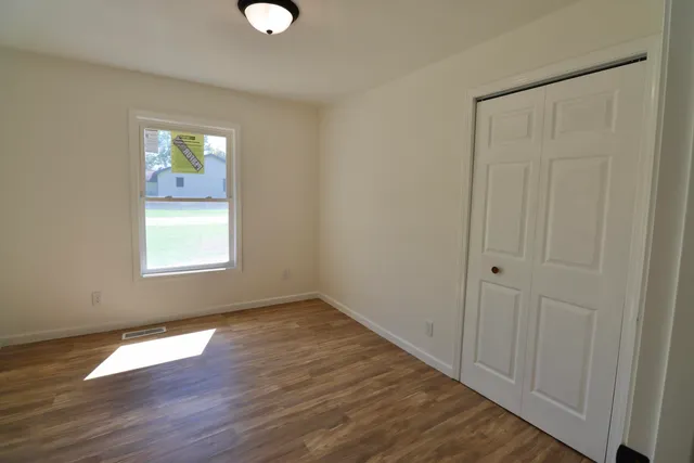 a view of an empty room with wooden floor and a window