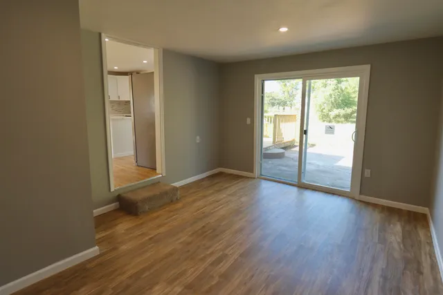 an empty room with wooden floor and windows