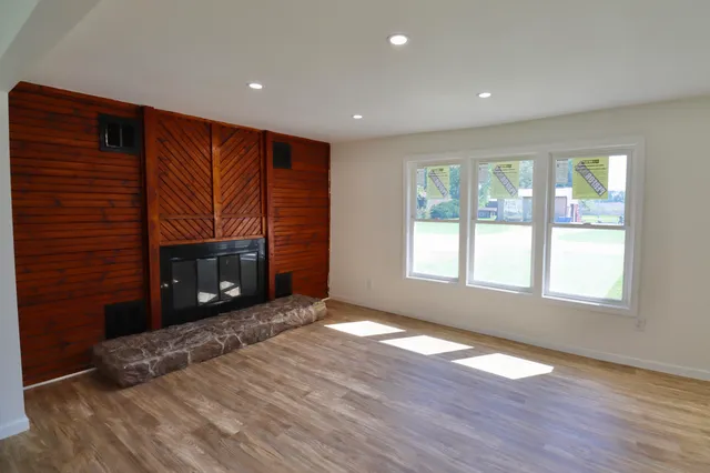 a big room with wooden floor fireplace and windows