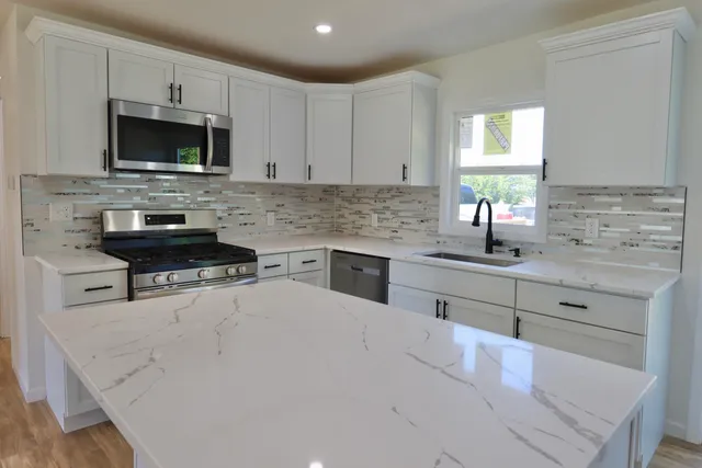 a kitchen with stainless steel appliances a stove sink microwave and cabinets