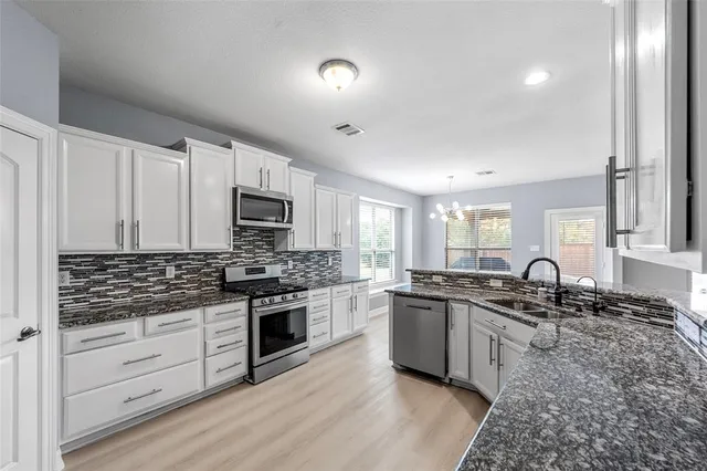 a kitchen with granite countertop a sink and stainless steel appliances