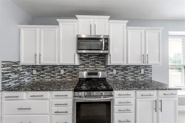 a kitchen with granite countertop a stove sink and microwave