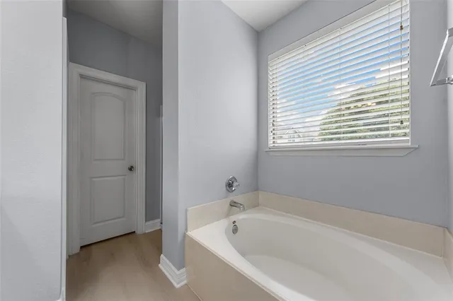 a white bath tub sitting in a bathroom next to a window
