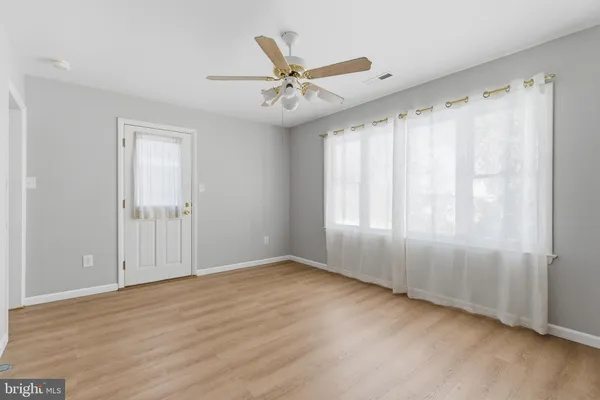 an empty room with windows and fan