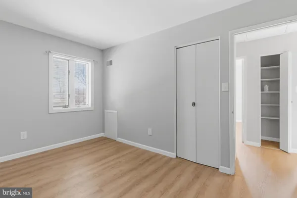 a view of an empty room with closet and a window