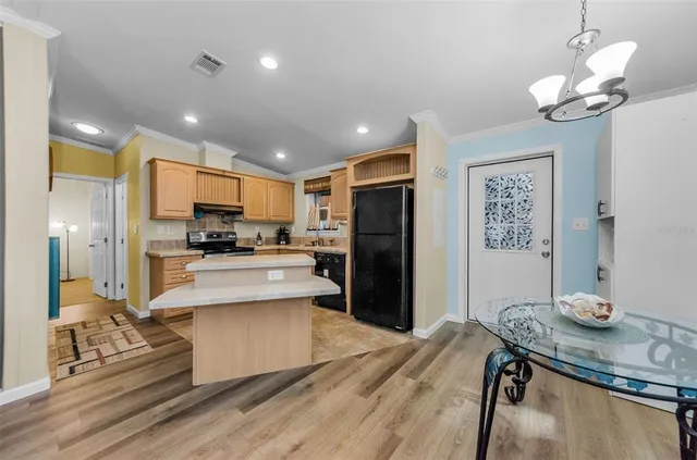 a large kitchen with a refrigerator a stove a sink a dining table and chairs